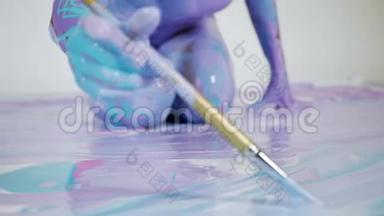 瑜伽女人坐在画着抽象图案和颜料的画布上